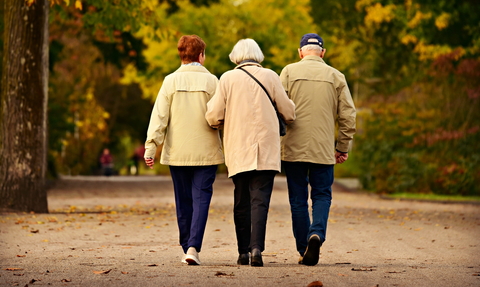 Three older people walking on a country path