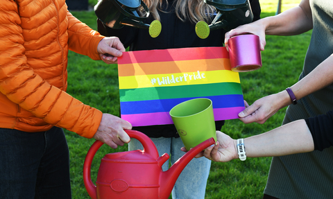 WilderPride image with watering cans plant pots all being held by various people