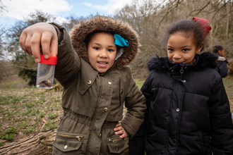 Two children looking at some wildlife in a specimen jar at Robinswood Hill