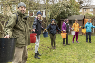 community members passing buckets in a row in back garden