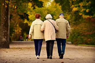 Three older people walking on a country path