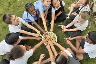 children excitedly pointing at the potatoes that they grew