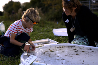 Claire watching a child investigating creatures found in the river eye