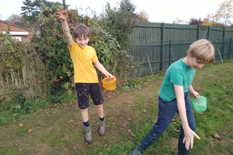 Two primary school children sowing wildflower seeds in a local park