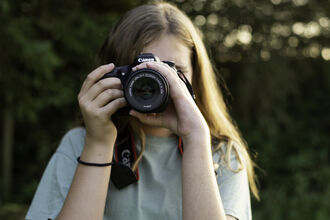 A person with long hair pointing a camera at the photo 