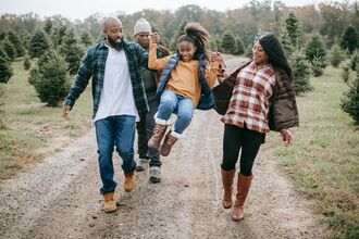 A family walks with a girl held aloft between them
