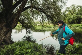 A Man in a blue jacket pond dipping