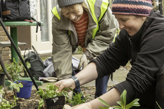 Two women with pots of plants gardening