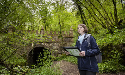 Habimapper Volunteer standing in front of bridge holding clipboard with species identification information on