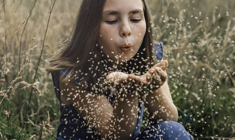 child blowing seeds