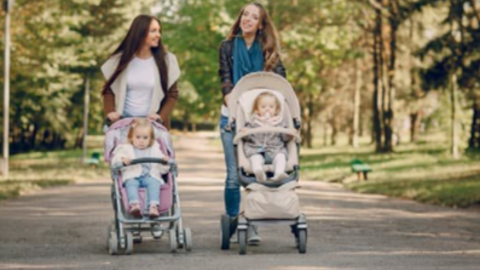 Two mums with children in pushchairs on a woodland path