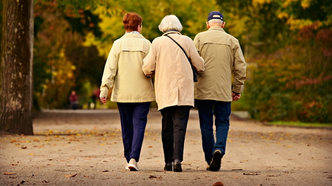 Three older people walking on a country path