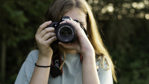 A person with long hair pointing a camera at the photo 