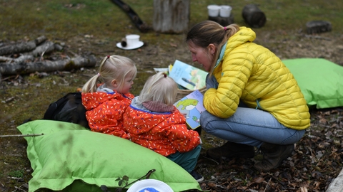 Adult reading to two children in a nature reserve