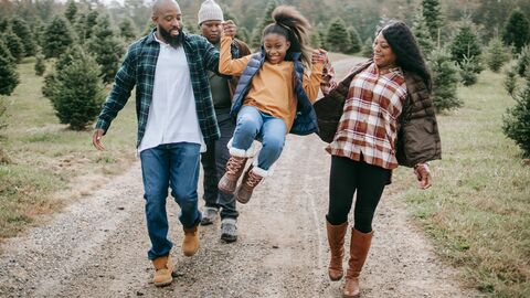 A family walks with a girl held aloft between them