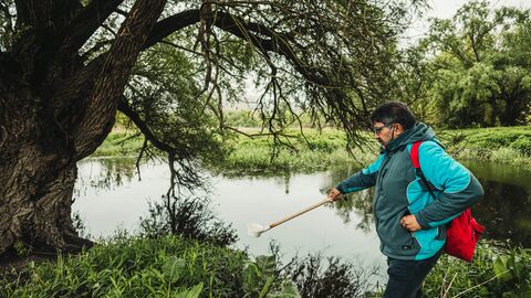 A Man in a blue jacket pond dipping