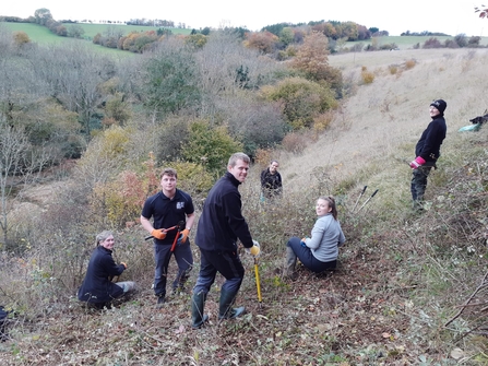 Group of Wild Trainees around clump of bramble they are clearing.
