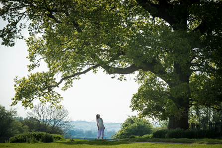 Woman standing beneath tree looking up