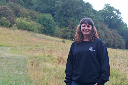 Hannah standing in a field with trees behind her