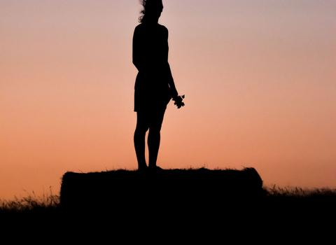 Woman_silhouette_standing_on_a_platform_during_sunset
