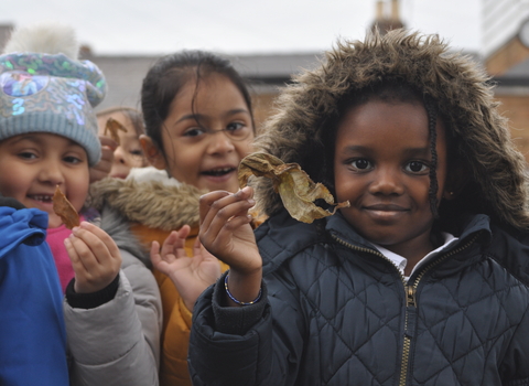 children holding autumn treasures seeds and leaves