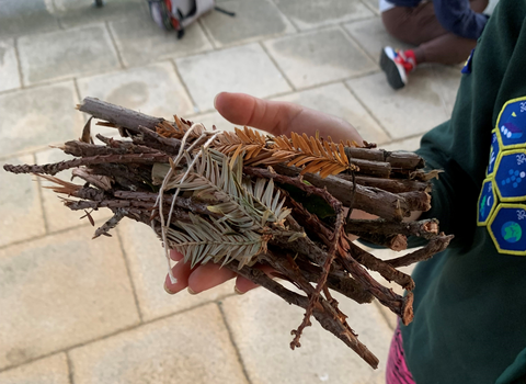 A child holding a pile of twigs and leaves to go into an insect hotel