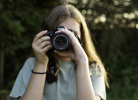 A person with long hair pointing a camera at the photo 